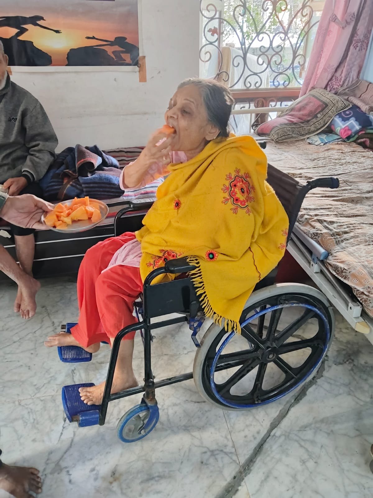 An elder in a wheelchair enjoying fruit